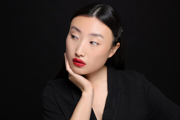 Portrait of beautiful young Asian woman on black background