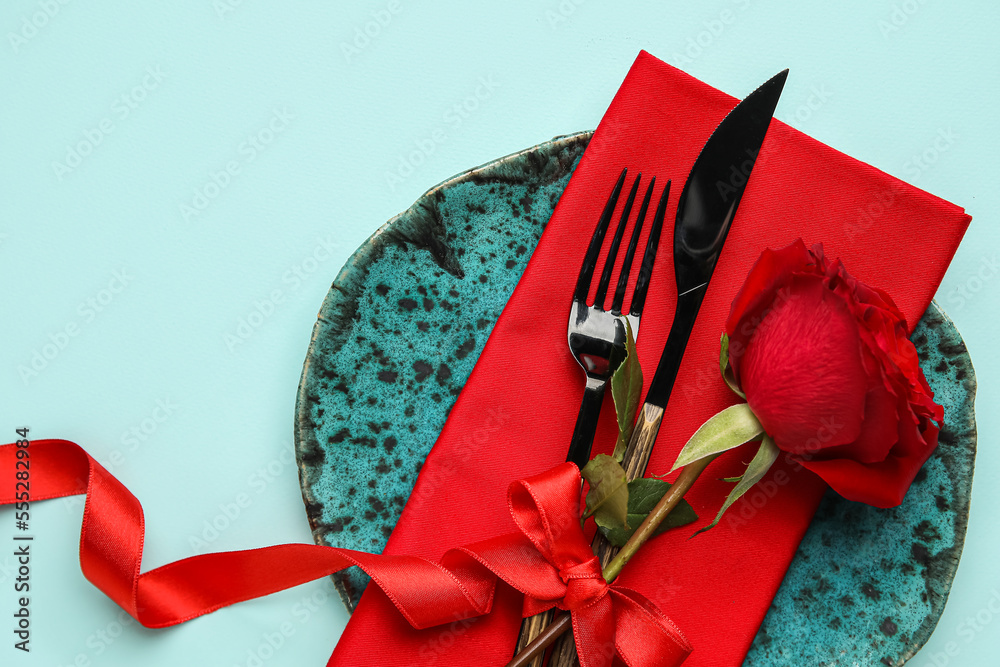 Table setting for Valentine's Day with red rose and bow on color background