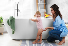 Mother Playing With Her Daughter Near Tub In Bathroom