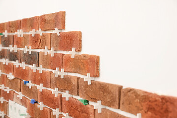 Decorative bricks with tile leveling system on white wall in room