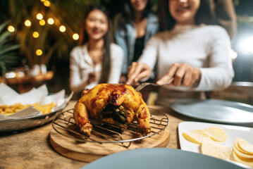 Happy Asian friends cheering with roasted turkey dinner outdoor - Group of people having fun in new year party. People, food and drink lifestyle concept Night Party, people and celebration concept.