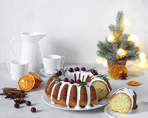 Christmas cake, pudding on white plate with dried oranges and cups for coffee on the background. Copy space.