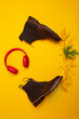 Flatlay Of Premium Dark Brown Grain Brogue Derby Boots Made of Calf Leather with Rubber Sole Placed With Yellow Maple Leaves and Headphones Over Yellow.