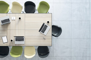 Poster - Work in progress concept with top view on wooden meeting table with laptops and coffee mugs surrounded by white, green and black chairs. 3D rendering