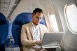© bongkarn - A professional and focused businessman using a laptop during the flight.
