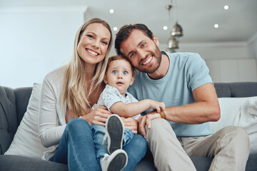 Poster - Happy, smile and portrait of a family on a sofa relaxing, bonding and holding their child at their home. Mother, father and baby boy sitting in the living room together with love, care and happiness.