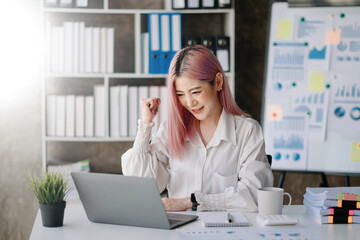 Asian business woman are delighted and happy with the work they do on their tablet, laptop and taking notes at the office.