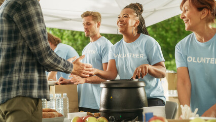 Positive Group of Young Adult Volunteers Serving Free Food for Poor People in Need. Charity Workers Help Members of the Community. Humanitarian Aid to Refugees and Immigrants.