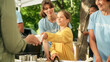 © Gorodenkoff - Amazing Young Girl Helping Volunteers in Humanitarian Aid Center, Handing Out Free Food for Local Community in Need. Team of Charity Workers Work at a Local Food Bank Outdoors Event.
