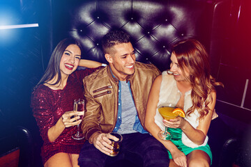 Friends, club and party drinking alcohol at disco event, concert or happy hour for new years celebration together. Man and women with smile relaxing, clubbing and having fun at rave or nightclub