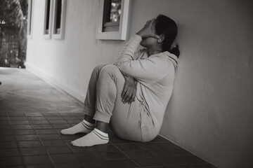 Wall Mural - Schizophrenia with lonely and sad in mental health depression concept. Depressed woman sitting against floor at home with dark room feeling miserable. Women are depressed, fearful and unhappy.