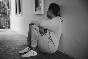 Wall Mural - Schizophrenia with lonely and sad in mental health depression concept. Depressed woman sitting against floor at home with dark room feeling miserable. Women are depressed, fearful and unhappy.