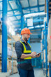 © ND STOCK - Warehouse workers in helmets checking goods and supplies on shelves with goods background in warehouse worker packing in a large warehouse in a large warehouse. Logistics industry concept.