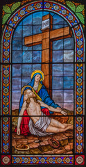 DOMODOSSOLA, ITALY - JULY 19, 2022: The Pieta on the stained glass in church Chiesa dei Santi Gervasio e Protasio by Luigi Fontana from 19. cent.