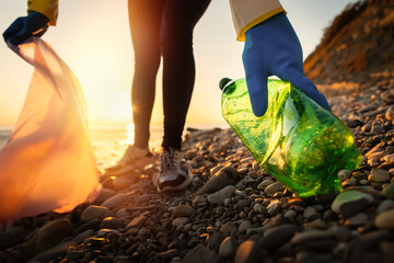 Conservation of ecology and Earth Day. A volunteer collects plastic bottles by the sea. Coastal cleanup for recycling. World environment day and global environmental pollution