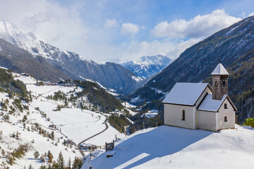 Canvas Print - Church on a hill in a snowy alp valley