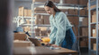 © Gorodenkoff - Small Business Owner of an Online Store Works on Laptop Computer while Standing at Her Desk in Warehouse. Female Employee Packing a Stylish Yellow Jumper in the Room with Shelves Full of Parcels.