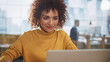 © Gorodenkoff - Beautiful Middle Eastern Manager Sitting at a Desk in Creative Office. Young Stylish Female with Curly Hair Using Laptop Computer in Marketing Agency. Colleagues Working in the Background