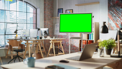 Wall Mural - Empty Conference Room for Team Meetings in Modern Creative Agency with Art on Walls and Desks with Computers. Office Space with Digital Green Screen Mock Up Chroma Key Monitor for Presentations.