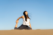 Relaxed Woman In Process Of Doing Asana On Sandy Ground