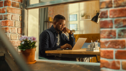 Poster - Young Handsome Male Using Laptop Computer, Sitting in Living Room in Apartment. African American Businessman Answering Emails, Writing a Business Plan from Home. Inside Apartment Window View.