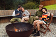 © Drobot Dean - Group of happy friends drinking tea while sitting by the bonfire