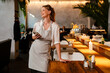 © Drobot Dean - Cheerful woman using mobile phone and looking aside while standing in restaurant