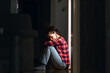 © _KUBE_ - Depression and mental disorder. Young Caucasian woman sits down on floor in despair and suffering in dark room. Side view. Concept of psychological health