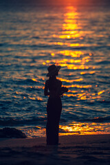 Wall Mural - Silhouette woman standing in ocean sea during summer sunset on blurred background.vertical