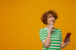 © Drobot Dean - Curly ginger woman in striped t-shirt smiling and using mobile phone