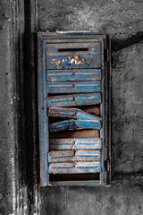 Colored blue old rusty broken mailbox hanging on a black and white wall	
