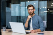 © Liubomir - .Serious pensive businessman in shirt thinking about decision sitting at table in modern office, man with beard is using laptop at work.