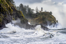 Surf Fills The Air With Salt Spray At Cape Disappointment With A Lighthouse Up On The Ridge; Ilwaco, Washington, United States Of America