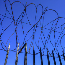 Barbed Wire Along The Top Of A Fence Against A Blue Sky, Vedado Neighbourhood; Havana, Cuba