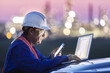 © Designpics - Man working on a laptop and smart phone with an oil refinery in the background; Alberta, Canada