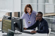 © AnnaStills - Asian young woman pointing at computer monitor and discussing new computer software with her colleague