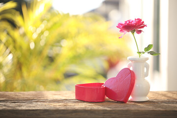 Wall Mural - Red rose in a white vase and heart box on wooden table