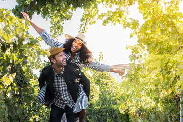 Wall Mural - happy young interracial couple on holiday in a vineyard.