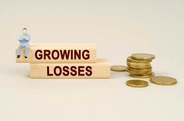 Wall Mural - On the table are coins, wooden plates with the inscription - Growing losses