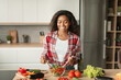 © Prostock-studio - Satisfied glad millennial black female preparing salad at table with organic vegetables, has fun at spare time