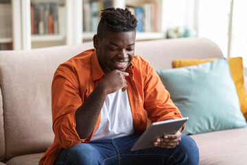 Wall Mural - Happy young black man watching video on digital tablet