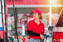 Attendant Service Female Worker Refuelling Car At Gas Station. Assistant Woman Wear Red Uniform And Red Hat Refuelling Car At Petrol Station