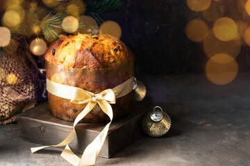 Traditional Italian Christmas cake, Panettoni  with raisins and candied fruits on wooden try with Christmas tree decoration and golden bokeh