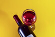 Glass and bottle of red wine on a yellow background. View from above.