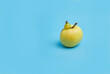Ugly yellow apple on a blue background. Funny, unnormal fruit or food waste concept. Image with copy space, horizontal orientation. Copy space.