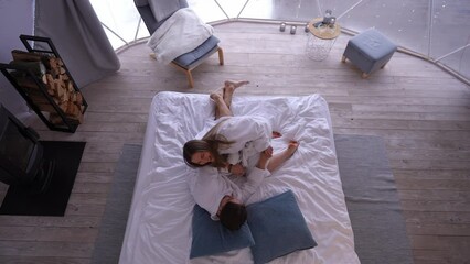 top view joyful young caucasian couple having fun cuddling on bed indoors. wide shot carefree relaxe