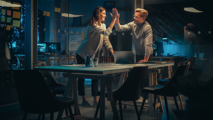 Aufkleber - Successful Young Small Business Owners Communicating at a Meeting in Office at Night. Talented Female and Excited Man Discussing Future Company Policy. Managers High Five Each Other
