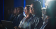 © Gorodenkoff - Black Female Sitting in Dark Crowded Auditorium at an International Business Conference. Multiethnic African Woman Using Laptop Computer. Delegate Watching Presentation About New Financial Solutions.