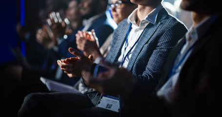 Close Up on Hands of a Crowd of People Clapping in Dark Conference Hall During a Motivational Keynote Presentation. Business Technology Summit Auditorium Room Full of Delegates.