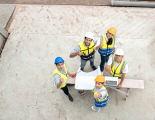 Engineer man and architect teamwork wear safety helmet meeting at construction site with blueprint for engineering project design, top view. High angle view of construction workers brainstorming.